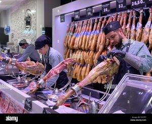 a-spanish-jamon-serrano-ham-leg-getting-sliced-packaged-by-workers-in-a-supermarket-in-barcelo...jpg